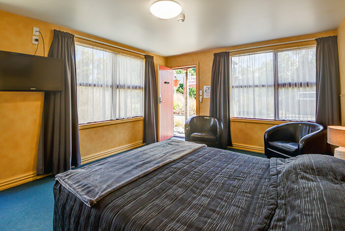 Inside the Superior Queen room at Red Tussock motel showing a Queen bed and two seats.